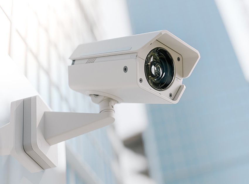 A white wall-mounted surveillance camera.